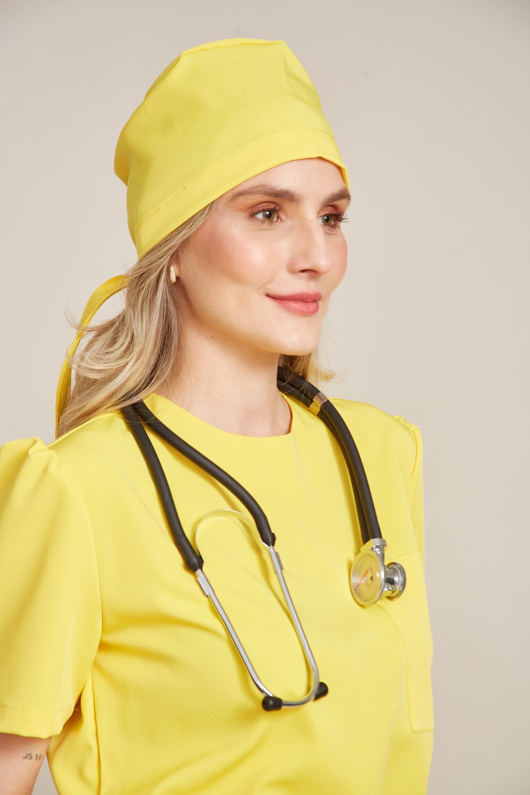 Profissional de saúde com conjunto amarelo e touca da mesma cor
